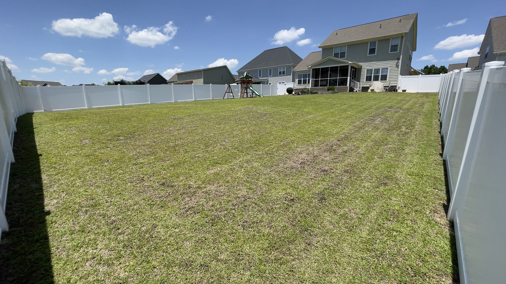 A fenced backyard mowed with clean stripes in Hope Mills