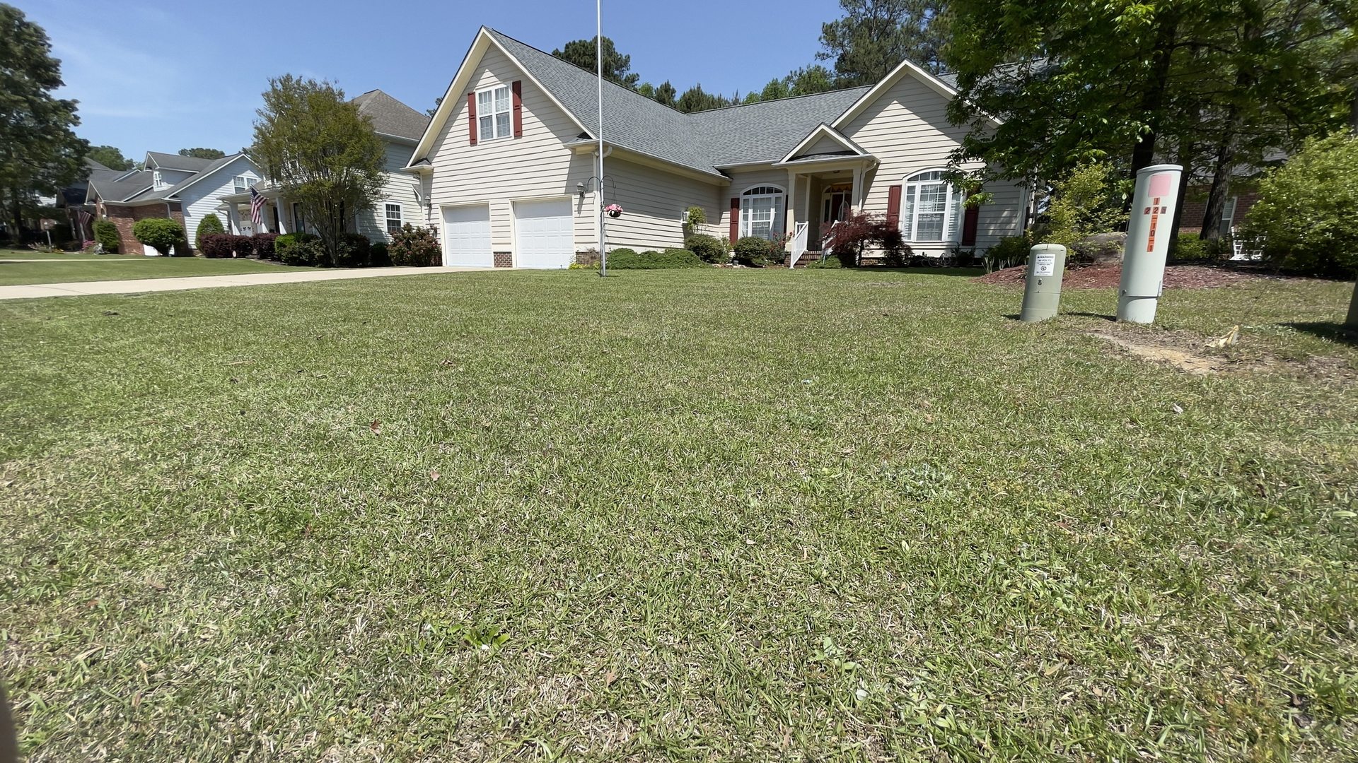 A tan two-story home with a freshly cut front lawn